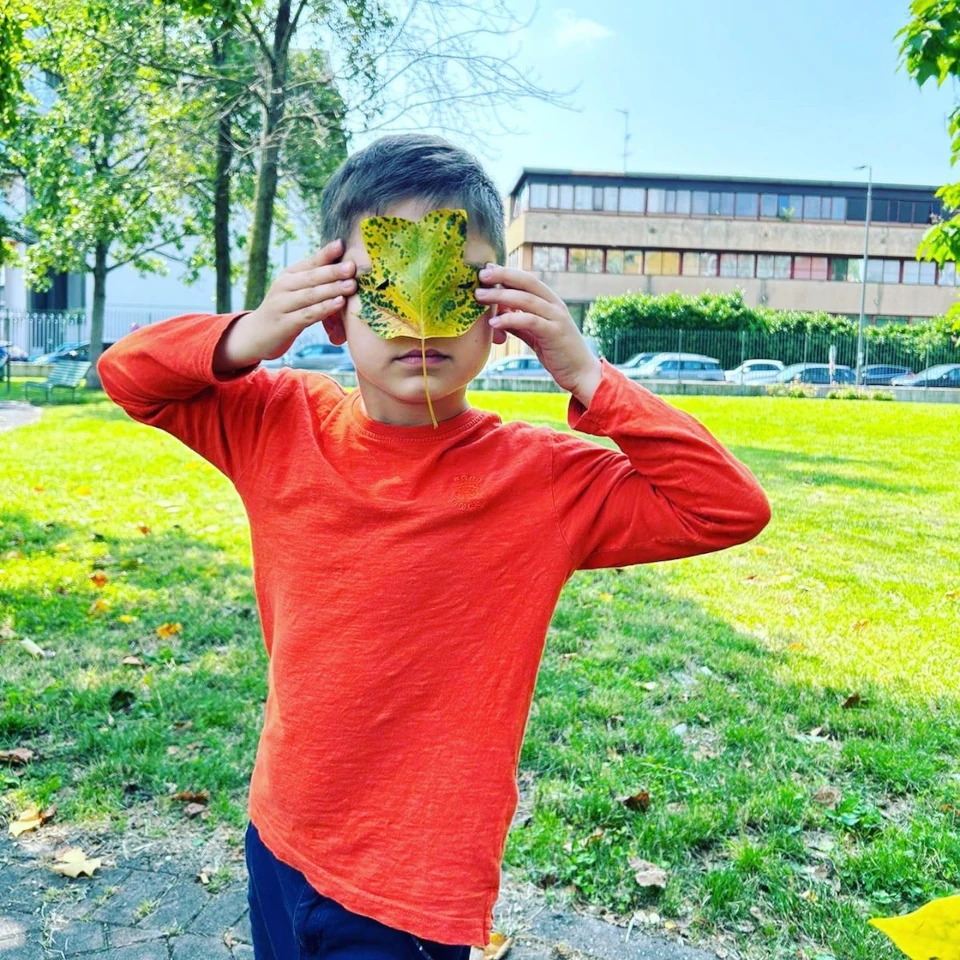 Bambino con foglia davanti al viso esplora la natura con Coibambini.