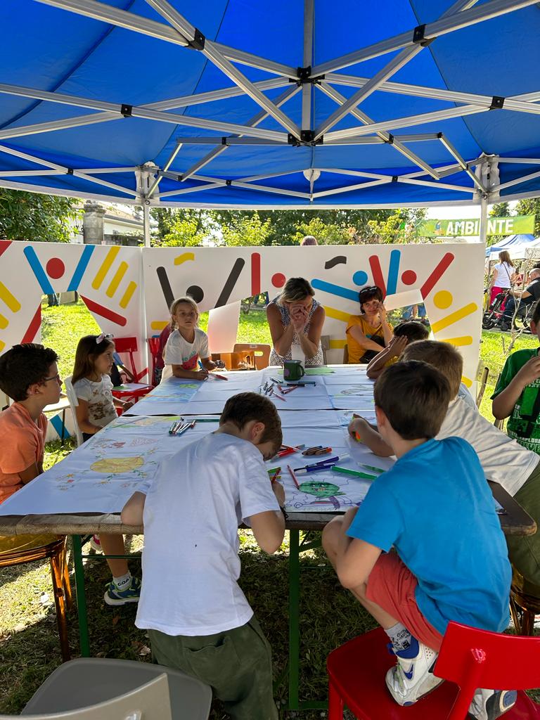 Bambini e adulti impegnati in attività creative sotto un gazebo Coibambini.